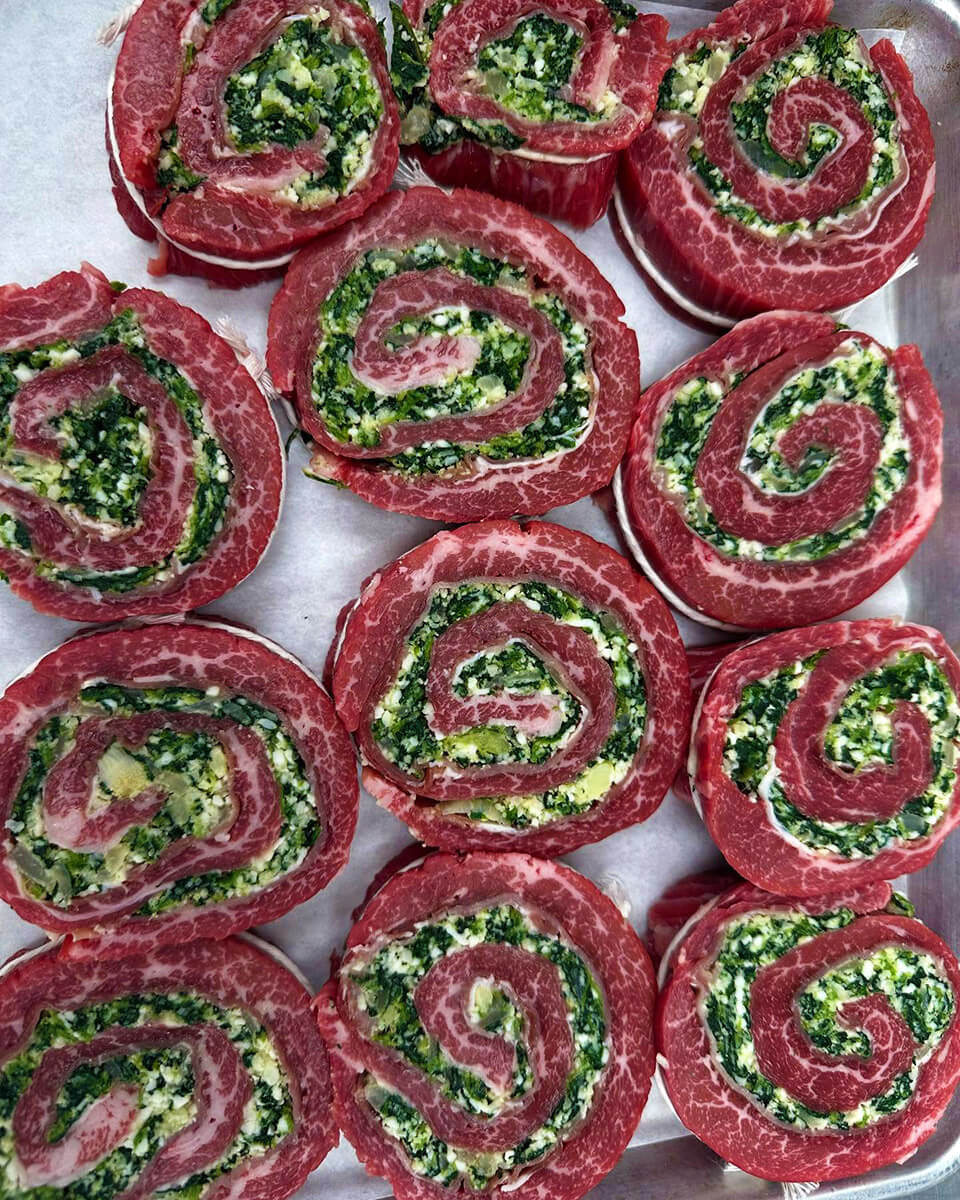 Spinach and feta-stuffed beef pinwheels on a tray